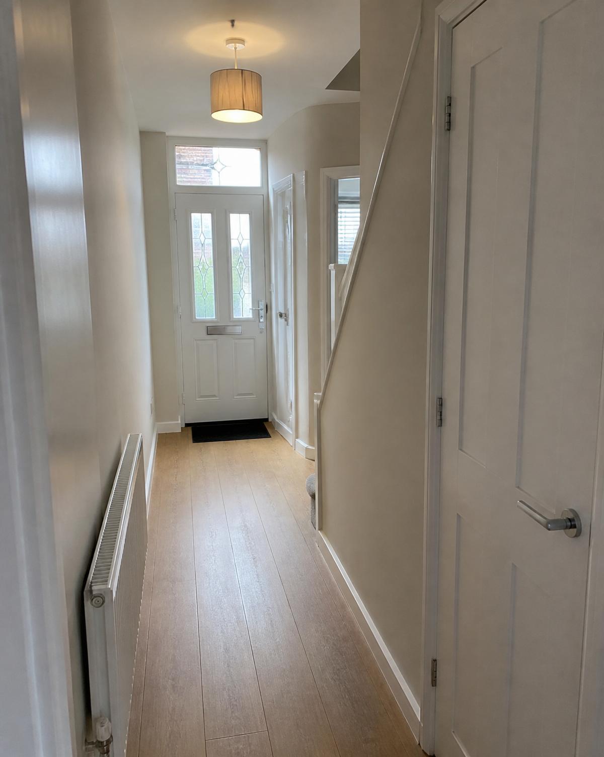 Sage green panelled hallway with oak floor and console table